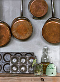 Copper pots and pans and old baking tins on grey kitchen wall