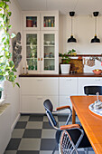 Dining room with retro furniture and black and white checkered floor, kitchen in the background