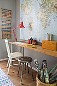 Desk corner in children's room with world map, red lamp and model cars