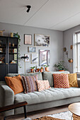 Living room with grey sofa, colourful cushions and wall decoration