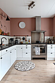 White kitchen with pink wall paint and modern stainless steel appliances