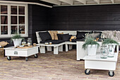 Covered terrace with white wooden furniture and black cushions