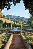 Formaler Kräutergarten mit Brunnen und Bergblick im Hintergrund