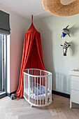 Baby cot with red canopy and wall decoration in the children's room