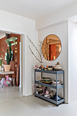 Metal shelf with ceramic crockery and branches in passageway area