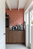 Coffee corner in kitchen with wooden cabinets and geometric wall design