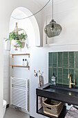 Modern bathroom with black washbasin, gold tap and green tiles