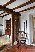 Wooden chair and wall decoration in rustic entrance area with rustic wooden beams