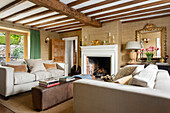 Living room with exposed ceiling beams, fireplace and light-colored sofas