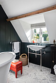 Bathroom with free-standing bathtub, sloping roof and herringbone mosaic tiles