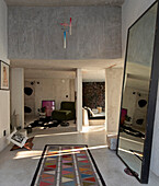 Loft with concrete walls, large mirror and carpet with a geometric pattern in the entrance area