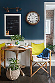 Dining area with wooden table and yellow director's chairs in front of dark blue wall