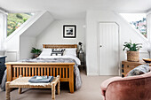 Attic room with wooden bed, fur throw and plants