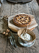 Nut cake on a rustic wooden table with whipped cream and vintage cutlery