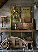 Rustikaler Tisch, Holzkiste und Fensterläden mit Lamellen vor Backsteinwand