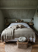 Attic bedroom with grey-painted walls and rustic wooden furniture