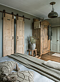 Country-style bedroom with wooden sliding doors and rustic wardrobe