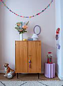 Colourful decoration with DIY garland over vintage chest of drawers