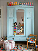 Hellblauer Vintage-Kleiderschrank im Kinderzimmer mit Spielzeug und Sitzpuff