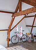 Attic bedroom with exposed wooden beams and decorative bicycle
