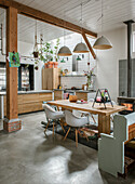 Open-plan kitchen with wooden table, white chairs and pendant lights