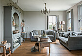 Living room with grey sofas, wooden table and chandelier