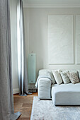 Hellgraues Sofa mit gemusterten Kissen und abstraktem Wandbild in modernem Wohnzimmer