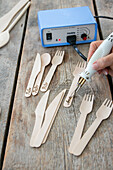 DIY wood engraving of cutlery with branding iron on wooden table