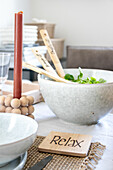 Table setting with white salad bowl and wooden trivet