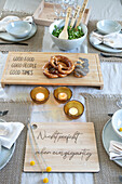 Table setting with pretzels, cold cuts and candlelights on wooden boards