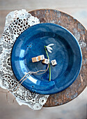 Blue ceramic bowl with snowdrops (Galanthus) and Scrabble letters on a wooden stool