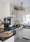 Kitchen corner with white cabinets, black counters and chandelier