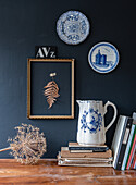 Vintage decoration with blue and white ceramic plates and antique jug against a dark wall