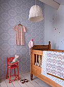 Children's room with patterned wallpaper in lace design, wooden crib and red chair