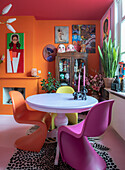 Colorful dining room with vintage decorations and modern art on an orange wall