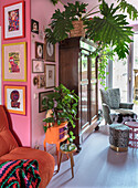 Living room designed in shades of pink with plants, orange vintage chest of drawers and wooden cabinet