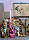 Pink candle holder with putto, vinegar and oil bottles, dachshund figurine and gold-decorated trays on kitchen worktop