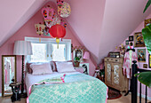 Schlafzimmer mit rosa Wänden, chinesischen Laternen und Vintage-Möbeln