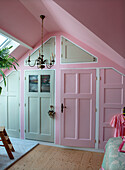 Attic room with pink walls, white doors and antique chandelier