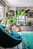 Bright living room with lots of houseplants and green armchair