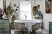 Freestanding vintage bathtub with flower and plant arrangements in the eclectic bathroom