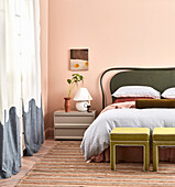 Bedroom with green headboard, pink walls and striped carpet