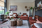 Cosy living room with brown velvet sofas and rustic, round wooden tables