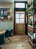 Dining area with wooden shelf, round dining table and green velvet chairs