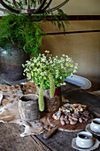 Rustic wooden table with bouquet of wild flowers and pieces of chocolate on wooden board