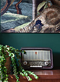 Vintage radio on wooden cabinet in front of green wall with elephant picture