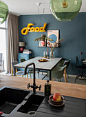 Dining area with blue-green wall paint, industrial lights and neon-coloured "Food" lettering