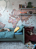 Children's room with bed, world map wallpaper and various toys