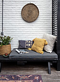 Garden lounge with colourful cushions and rattan wall decoration