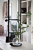 Eucalyptus branches in a glass vase on a white table in the living room